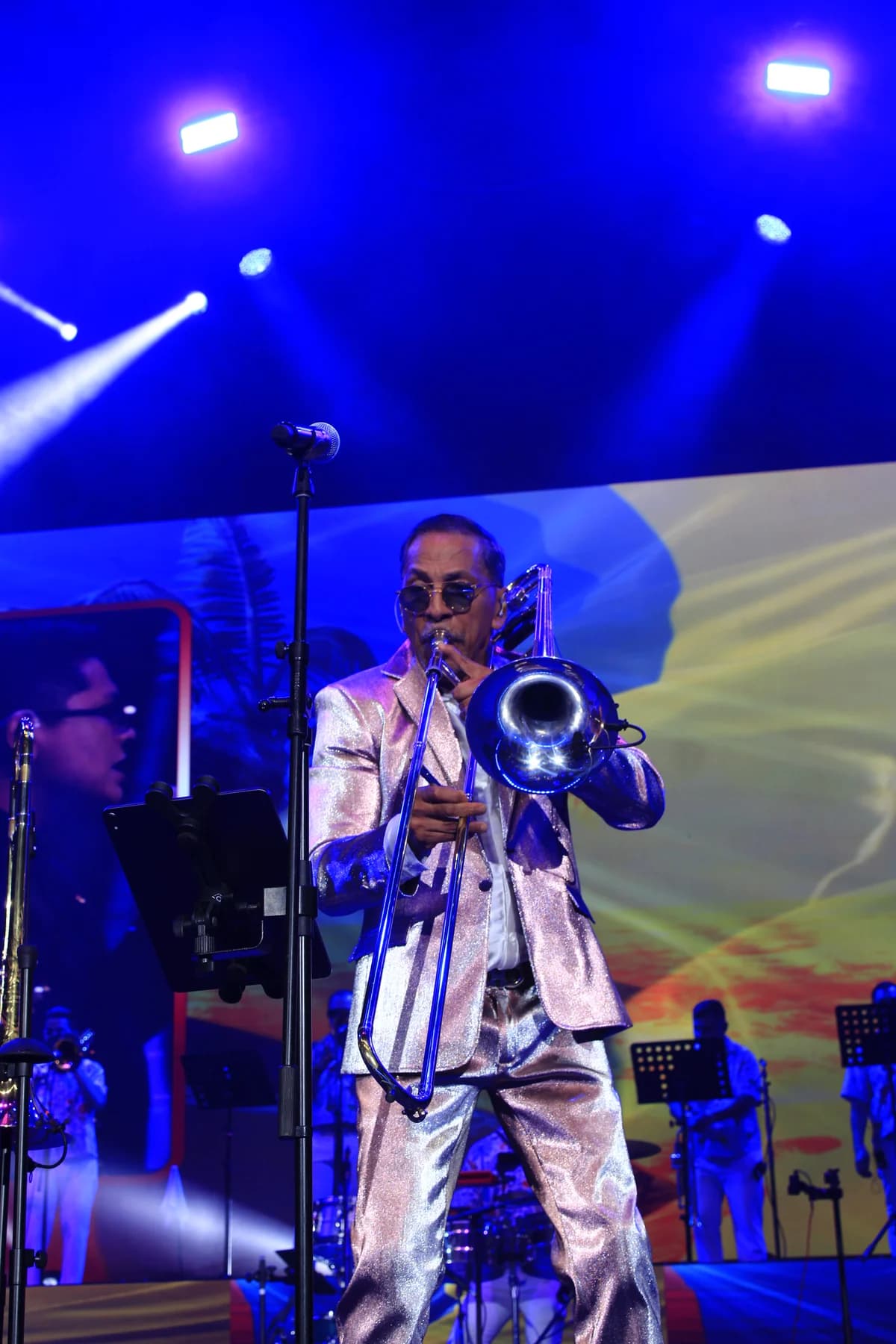 Alberto Barros toca el trombón bajo las luces azules del escenario