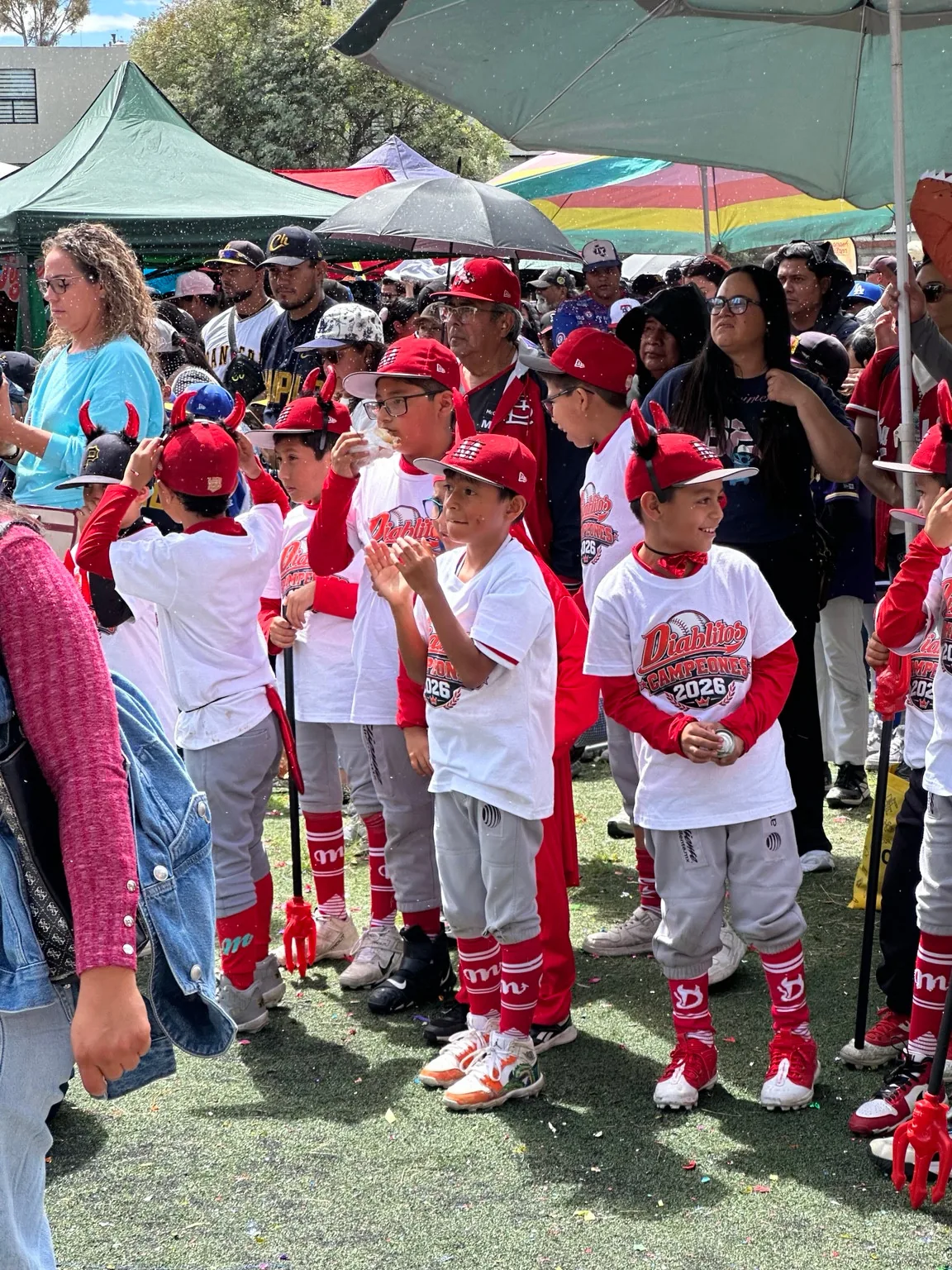 Jugadores y familiares reunidos junto al campo de béisbol.